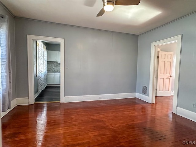 empty room with hardwood / wood-style flooring, a ceiling fan, baseboards, and visible vents