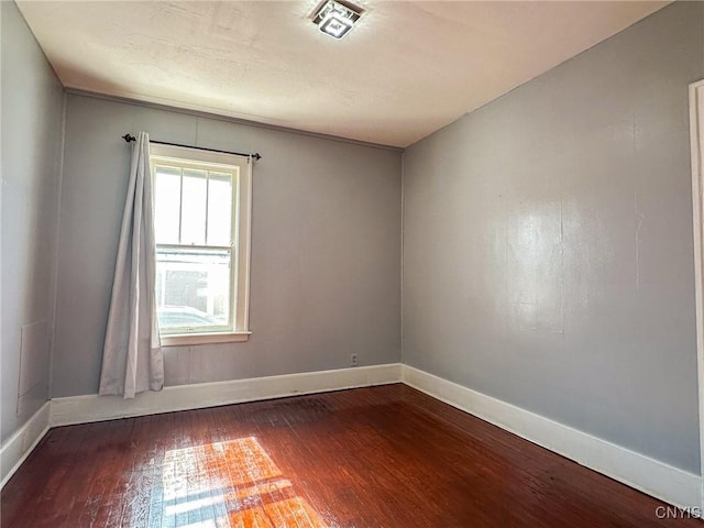 empty room featuring dark wood finished floors and baseboards