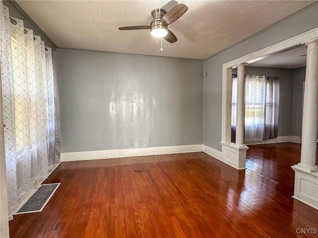 spare room featuring hardwood / wood-style flooring, a ceiling fan, visible vents, and ornate columns