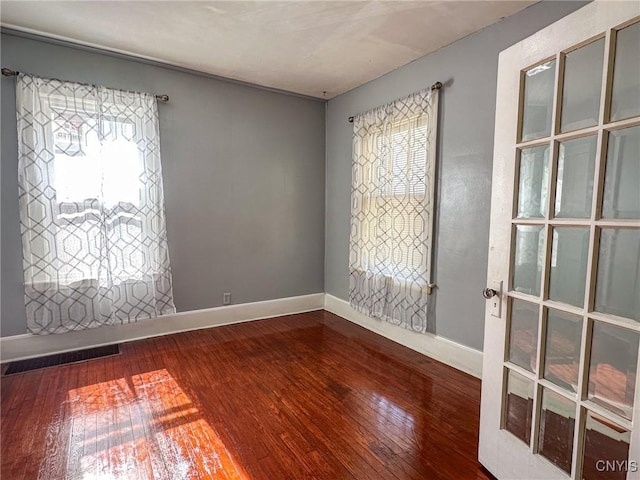 spare room with plenty of natural light, baseboards, and hardwood / wood-style floors