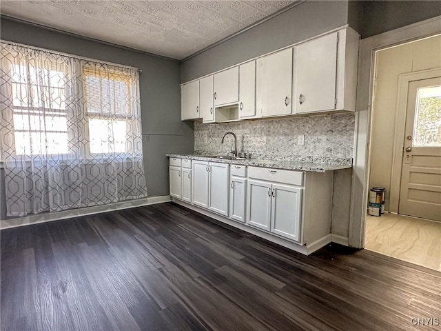 kitchen featuring backsplash, baseboards, dark wood finished floors, white cabinetry, and a sink