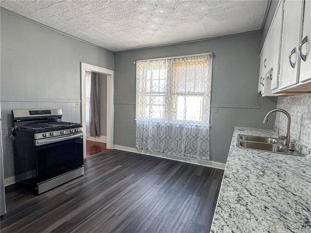 kitchen featuring stainless steel gas range oven, light countertops, dark wood-style floors, an ornate ceiling, and a sink