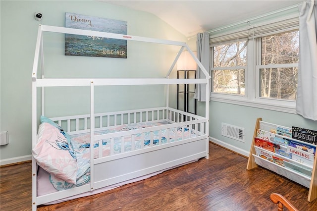 bedroom featuring visible vents, baseboards, wood finished floors, and vaulted ceiling