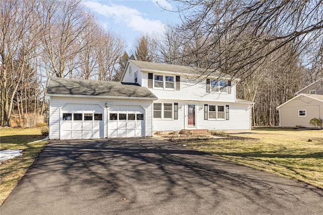 colonial-style house with a garage, a front lawn, and driveway