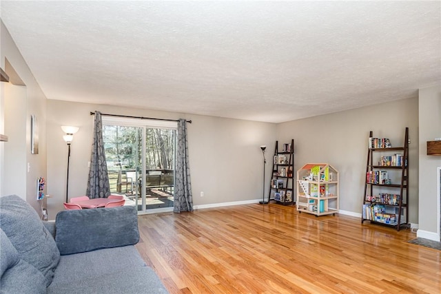 living room with baseboards, light wood finished floors, and a textured ceiling