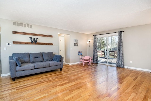 living area featuring light wood-style flooring, baseboards, and visible vents