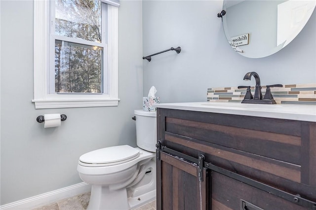 half bath with backsplash, baseboards, toilet, and vanity