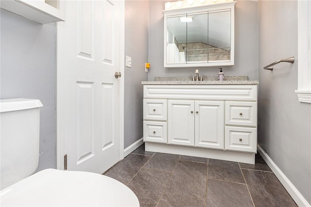 bathroom with vanity, toilet, and baseboards