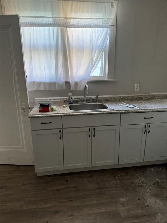 kitchen featuring dark wood finished floors, light stone countertops, white cabinetry, and a sink