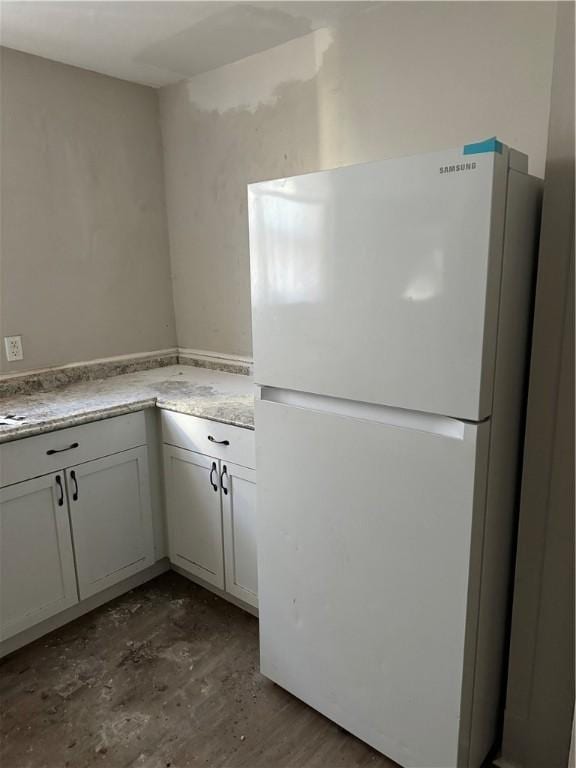 kitchen with white cabinetry, dark wood finished floors, light countertops, and freestanding refrigerator