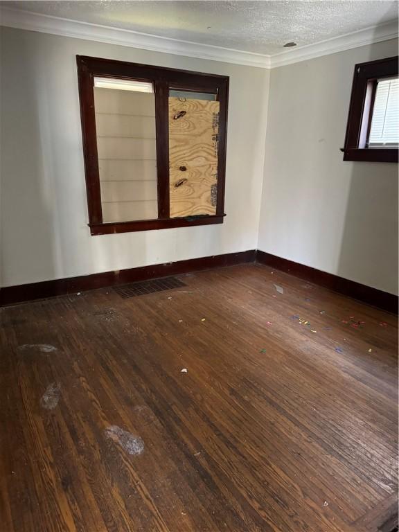 empty room featuring visible vents, ornamental molding, and hardwood / wood-style floors