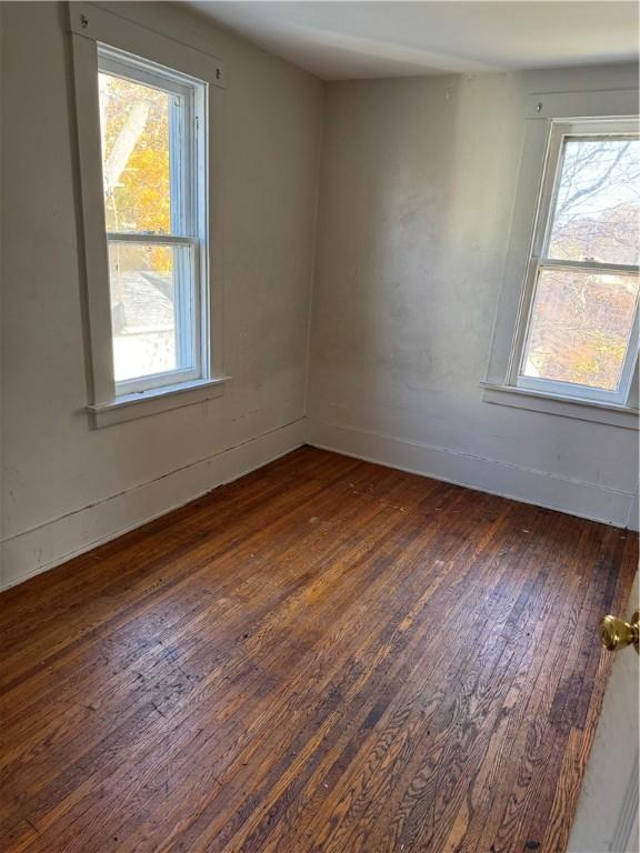 unfurnished room featuring baseboards and hardwood / wood-style flooring