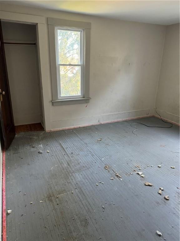 unfurnished bedroom featuring a closet, baseboards, and wood-type flooring