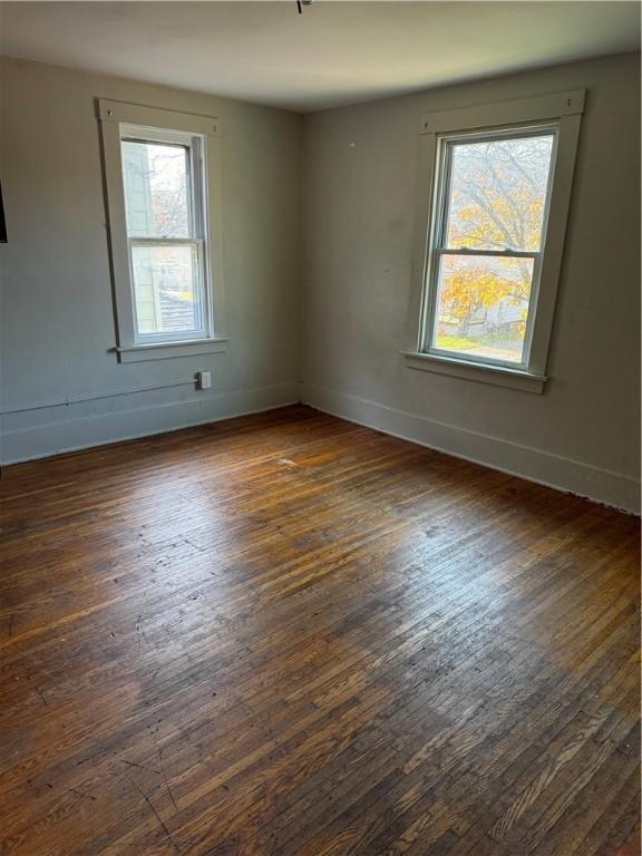 empty room featuring dark wood-type flooring and baseboards