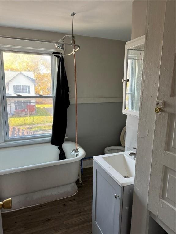 full bath featuring a freestanding tub, toilet, wood finished floors, washer / dryer, and vanity