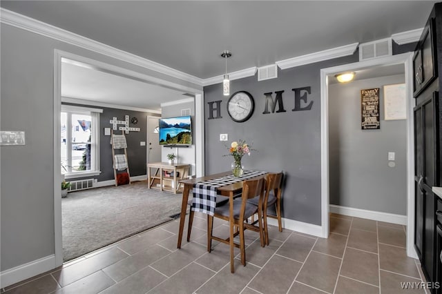 dining area featuring dark colored carpet, visible vents, dark tile patterned floors, and crown molding