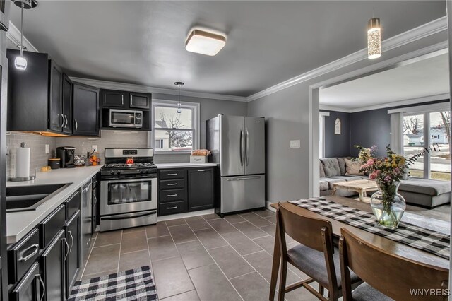 kitchen featuring dark tile patterned flooring, a sink, appliances with stainless steel finishes, light countertops, and decorative backsplash