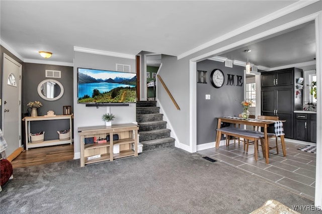 carpeted living room with stairs, visible vents, and ornamental molding