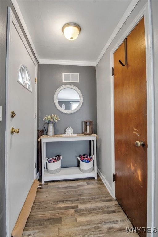 entrance foyer featuring visible vents, baseboards, wood finished floors, and crown molding