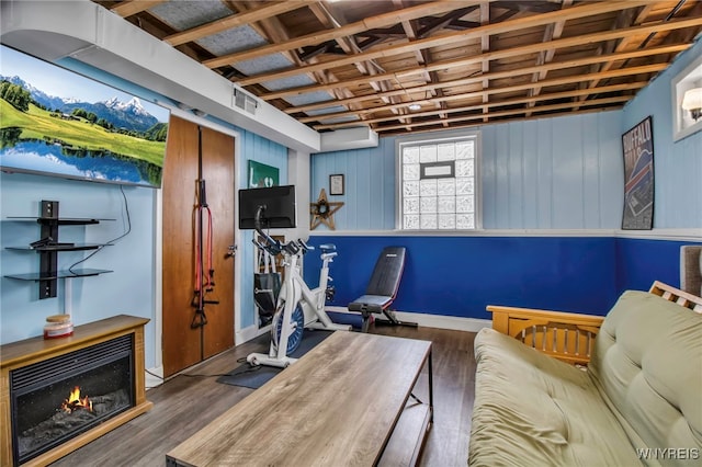 exercise room featuring visible vents, a warm lit fireplace, baseboards, and wood finished floors