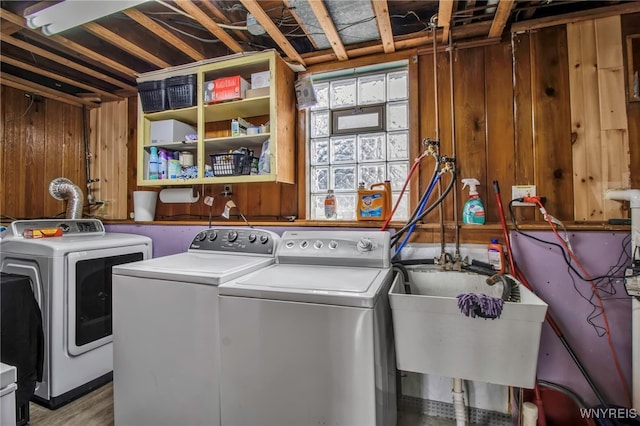 laundry room featuring a sink, separate washer and dryer, wooden walls, and laundry area