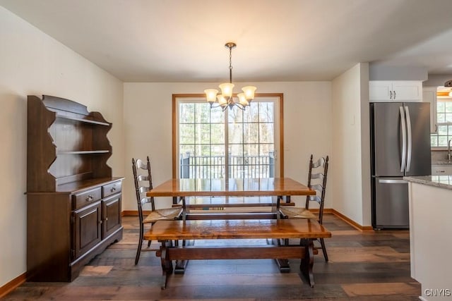 dining space featuring baseboards, a notable chandelier, and wood finished floors