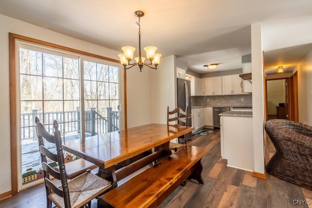 dining space with dark wood finished floors, a notable chandelier, and baseboards