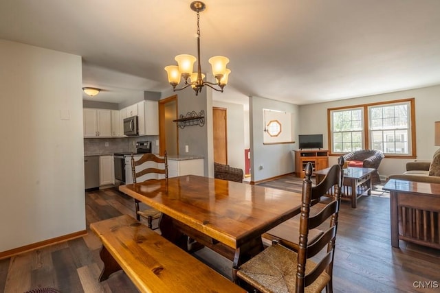 dining room featuring dark wood finished floors, a chandelier, and baseboards