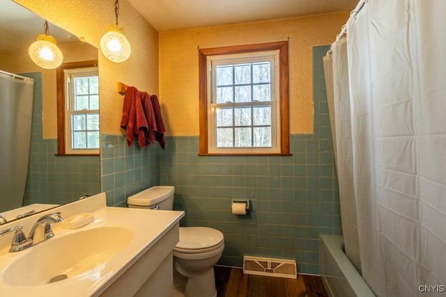 bathroom with visible vents, wallpapered walls, toilet, wainscoting, and wood finished floors