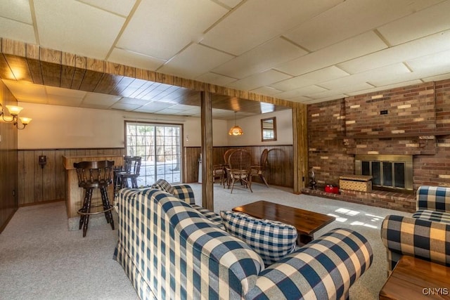 living area featuring a brick fireplace, carpet, and wainscoting