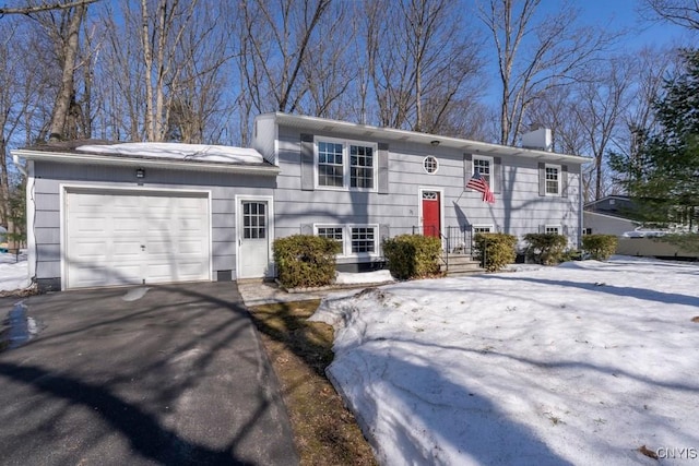 bi-level home featuring an attached garage, a chimney, and driveway