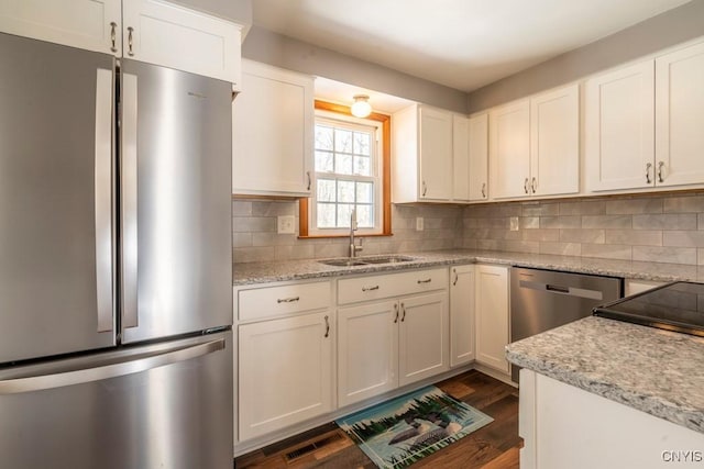 kitchen featuring a sink, backsplash, dark wood-style floors, appliances with stainless steel finishes, and white cabinets