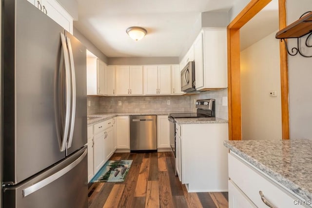 kitchen with dark wood finished floors, backsplash, appliances with stainless steel finishes, and light stone counters