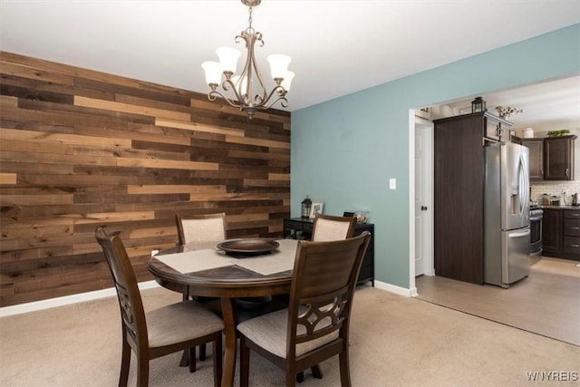 dining space with a notable chandelier, wooden walls, and baseboards