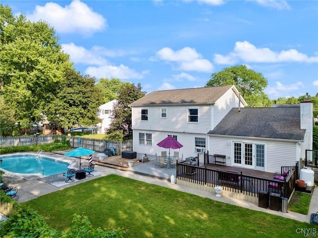 rear view of house with a deck, a yard, french doors, and a fenced in pool