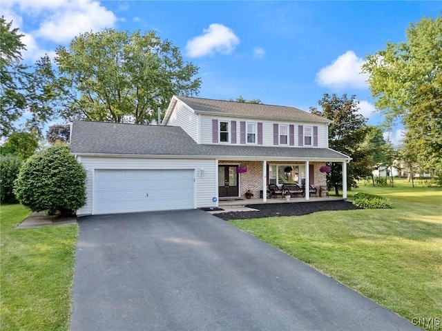 view of front of property featuring a porch, an attached garage, driveway, and a front yard