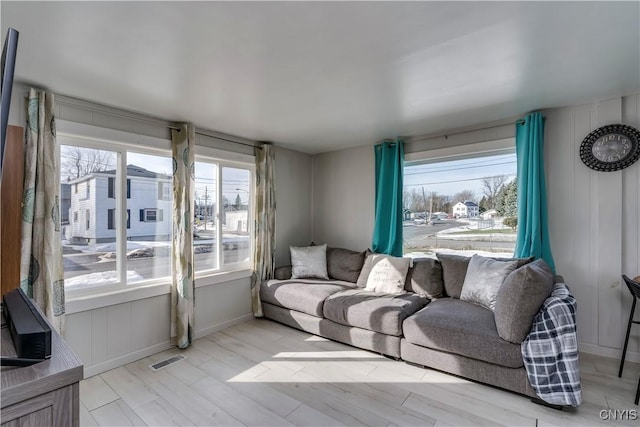 living area featuring plenty of natural light, light wood-style floors, visible vents, and baseboards