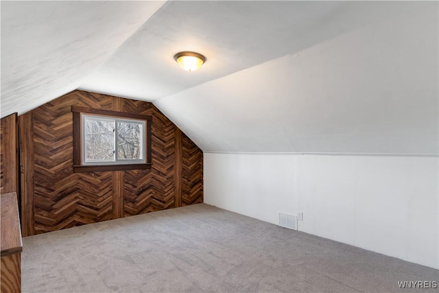 bonus room featuring vaulted ceiling, wooden walls, carpet flooring, and visible vents