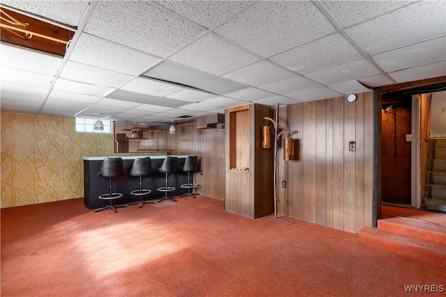 interior space with a bar, a drop ceiling, and carpet floors