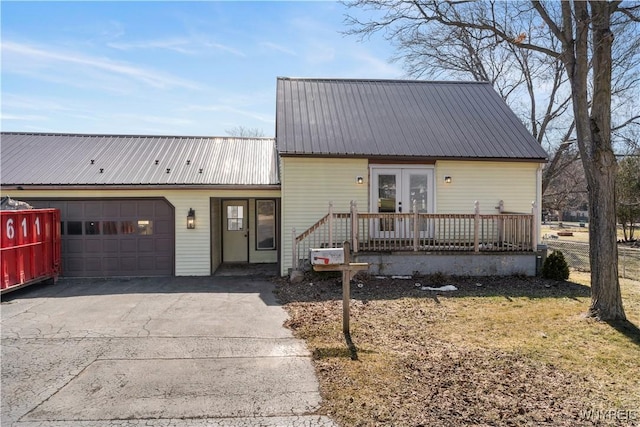 view of front facade with aphalt driveway, french doors, metal roof, and a garage