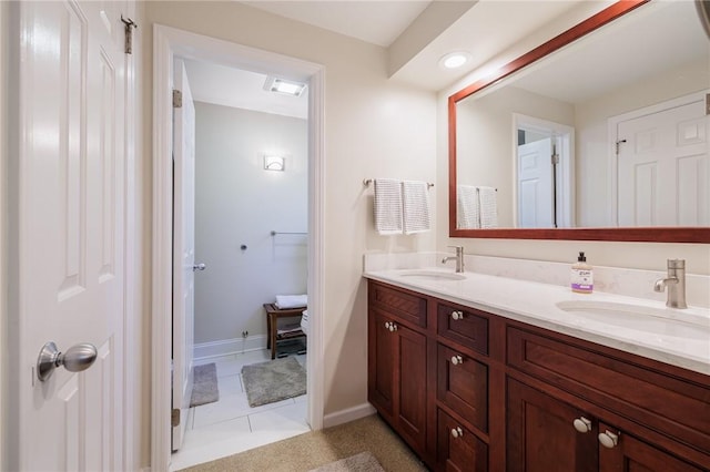 full bath featuring a sink, baseboards, double vanity, and tile patterned floors