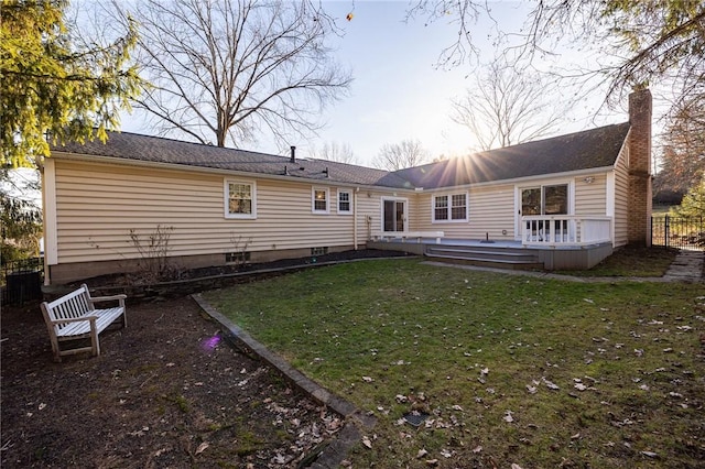 rear view of property with a wooden deck, a lawn, a chimney, and fence