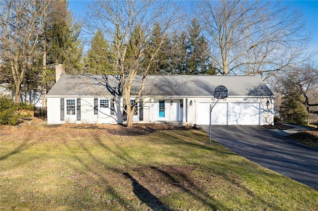 view of front facade featuring driveway, a front yard, a chimney, and an attached garage