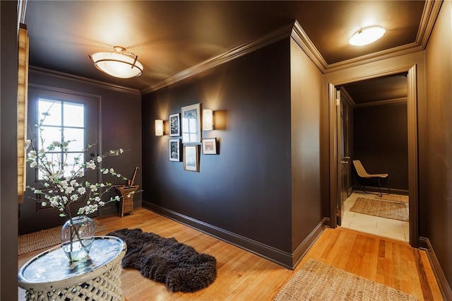 foyer entrance featuring baseboards, wood finished floors, and crown molding