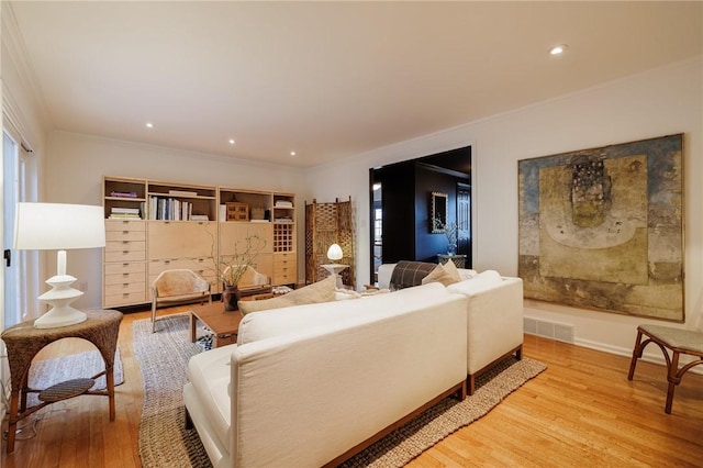 living area featuring recessed lighting, visible vents, light wood-style flooring, and ornamental molding