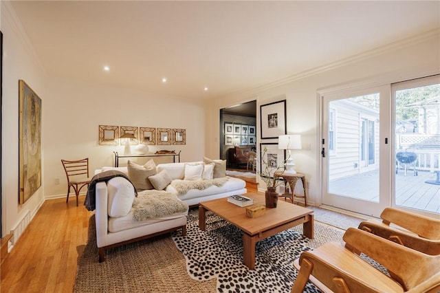 living room featuring visible vents, baseboards, light wood-style flooring, and crown molding