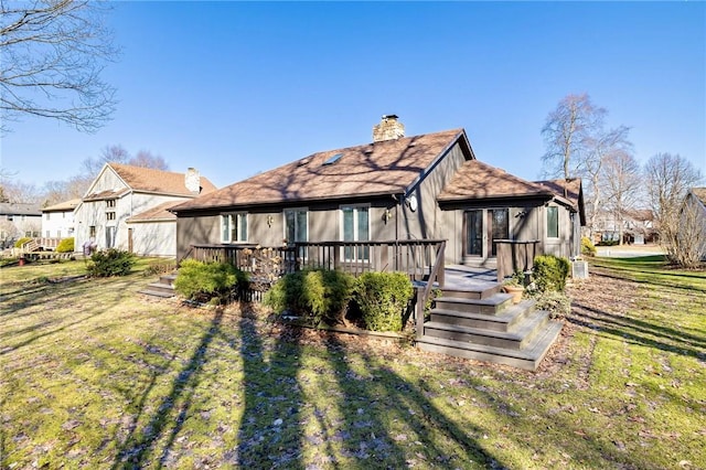 back of property featuring a wooden deck, a lawn, and a chimney