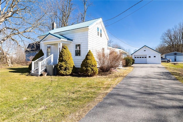 view of front of house featuring an outbuilding, a front lawn, metal roof, a garage, and a chimney