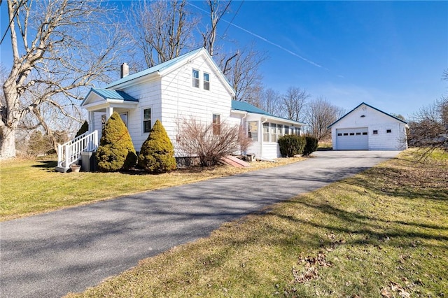 view of property exterior with a yard, a chimney, an outdoor structure, a garage, and metal roof