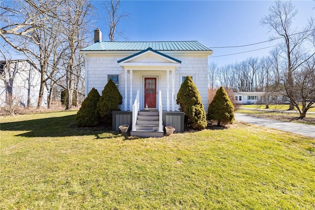 view of front of house featuring a chimney, a front lawn, and metal roof